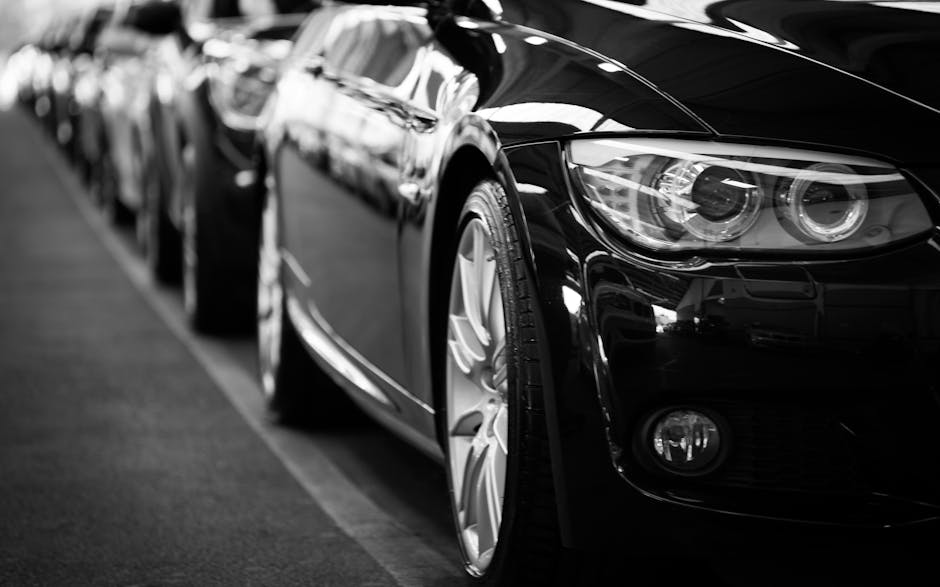 IAM Automobile Close-up black and white image of a luxury car line-up focusing on vehicle headlights.