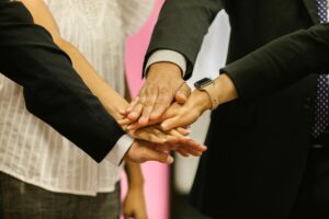 About iam icon advertising and marketing Close-up of colleagues huddling hands symbolizing teamwork and unity.